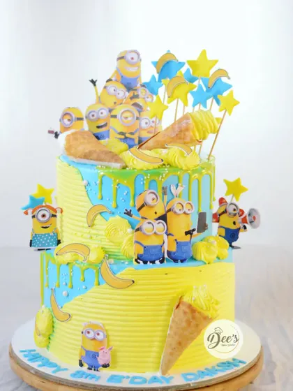 Bello. This two-tier Minions cake is pure fun, covered in yellow and blue buttercream and decorated with lots of mischievous Minions and their favorite snack, bananas.