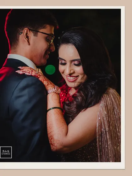 The couple shares a sweet, smiling moment, their embrace illuminated by soft lighting during their reception.
