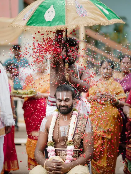 A ritual during the groom's procession, where he is showered with flower petals under a traditional umbrella.