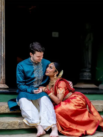 A cross-cultural couple shares a quiet moment on the steps, their different attires blending beautifully in the heritage setting.