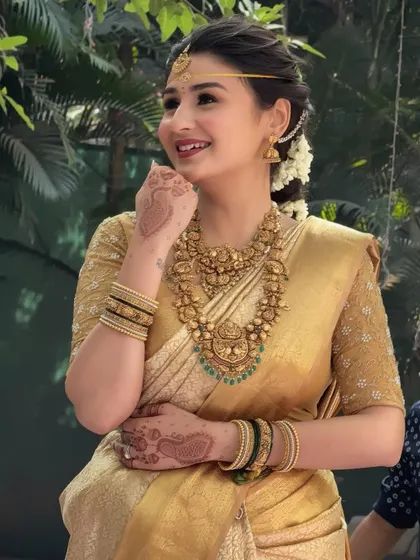 A candid shot of the South Indian bride, her face lit up with a smile. Her traditional attire and glowing makeup make her look like a queen.