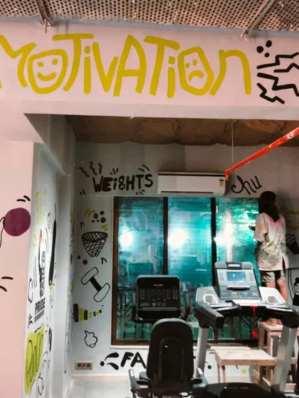 A wider view of the gym, where my doodle art covers the walls and ceiling, creating an immersive, high-energy environment. You can see me on a stool, adding the final touches.