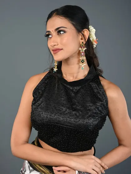 This black halter-neck blouse is fully beaded, giving it a subtle texture and sparkle. It's a sophisticated and modern choice for any occasion.