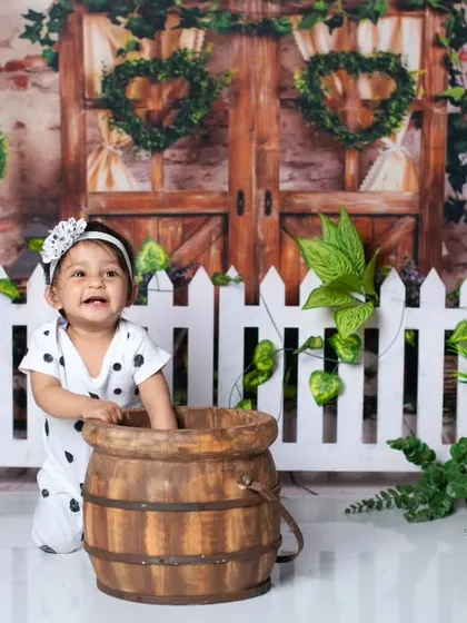 A joyful, candid moment of a baby girl playing in a barrel during her panda-themed session.