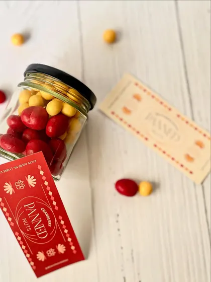 A jar of our colorful cranberry and butterscotch panned nuts, a vibrant and tasty part of our mini Rakhi hampers.
