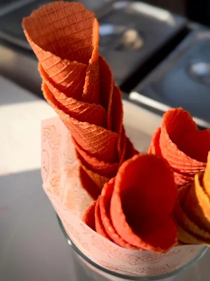 A close-up of our crisp, colorful waffle cones, stacked and ready for service. The vibrant red color adds a pop of fun to the dessert experience.