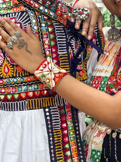 A close-up on the details that tie a couple's look together, like this embroidered cuff with cowrie shells, set against the intricate pattern of the man's tunic.