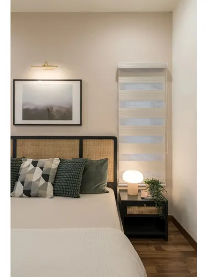 A bedroom that combines classic and contemporary elements, with a cane headboard, modern bedside lamp, and a neutral color palette.