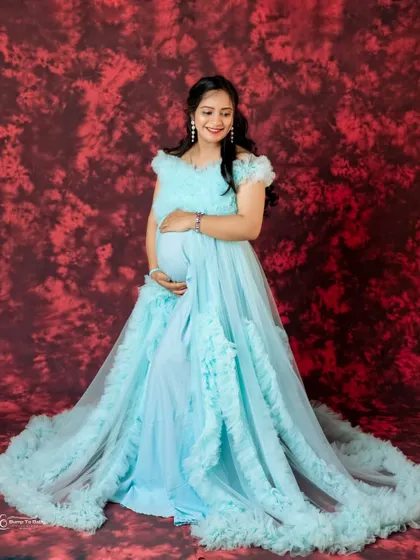 This stunning light blue ruffled gown features a long, dramatic train. It's a perfect choice for a fairytale-themed maternity or pre-wedding shoot.