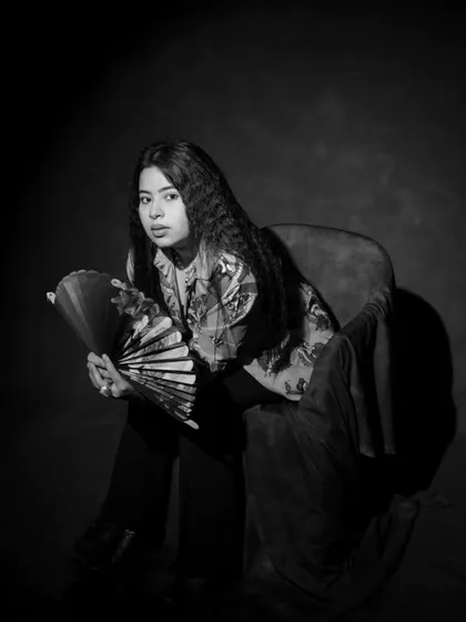 The same artistic portrait, this time in black and white. This version emphasizes the textures of the crimped hair and the fabrics, creating a timeless and dramatic feel.