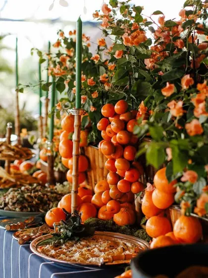 A bountiful food display where cascades of fresh oranges and bougainvillea are woven between the platters. This styling turns the buffet into a vibrant, decorative feature.