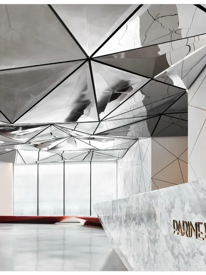 The reflection of the reception desk in the ceiling creates a sense of continuity and visual complexity. The design plays with perception and reality.