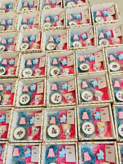 An overhead view of the baby shower boxes, filled with colorful shred, candles, and themed soaps.