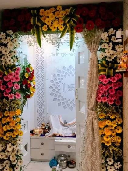 A full floral entrance for a home mandir. We used a rainbow of gerbera daisies and other colorful flowers to create a grand and welcoming archway leading into the serene, white prayer room.