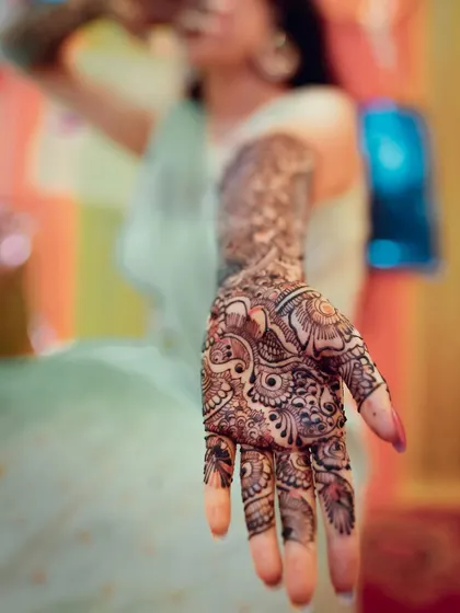 A close-up of a bride's hand, showing the rich, dark stain of her bridal mehendi.