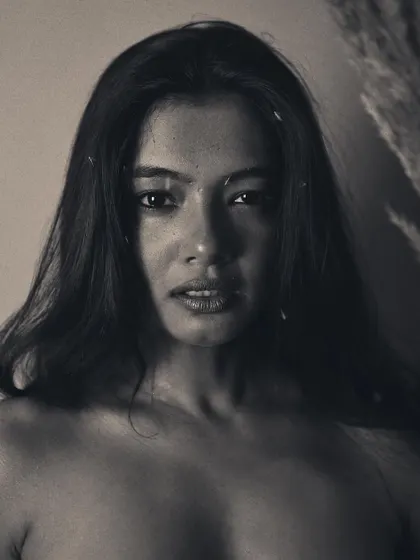 A direct and powerful gaze is the focus of this black and white portrait. The soft, grainy texture adds a timeless feel, while the simple composition keeps all the attention on the model's expressive face.