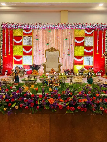 A wide shot showing how our offering display integrates with the overall stage design. The neatly arranged plates of fruits and sweets add a layer of tradition and abundance to the celebration.