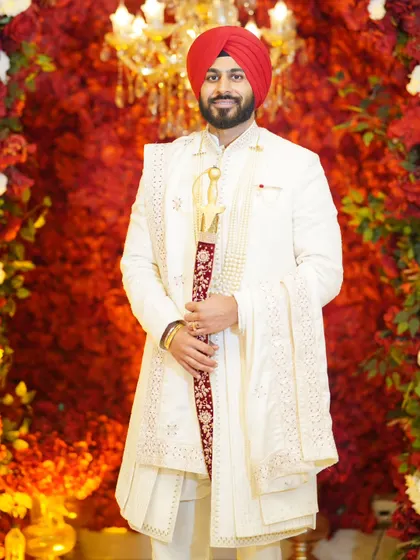 The groom deserves his own moment in the spotlight. This portrait captures the pride and elegance of the groom in his wedding sherwani, standing against a rich floral backdrop.