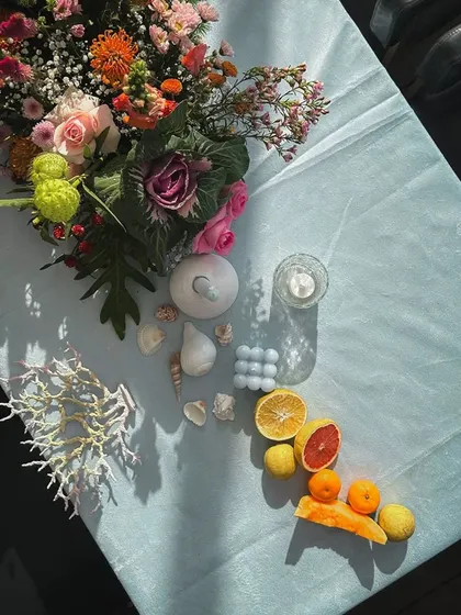 A beautiful tablescape for a seaside cocktail party. The light blue tablecloth, citrus fruit accents, and seashells create a fresh, coastal, and elegant feel.