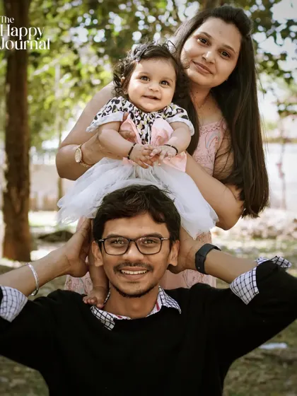A sweet family moment outdoors, with the baby sitting on her father's shoulders. This photo shows the fun and connection of a family enjoying time together.