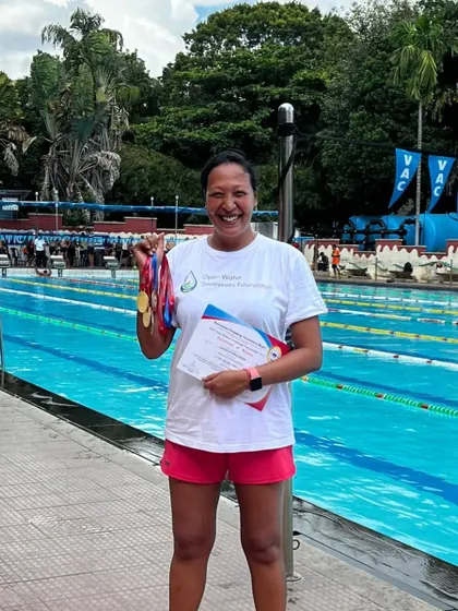 A triumphant smile from one of our masters swimmers, holding a handful of medals won at the state championships. This is what dedication looks like.