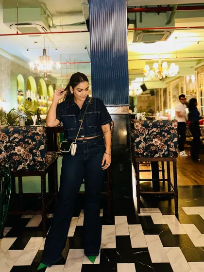 Denim on denim, but make it evening-ready. A cropped denim shirt paired with dark wash flared jeans and a pop of green from the pumps creates a sophisticated yet cool look.