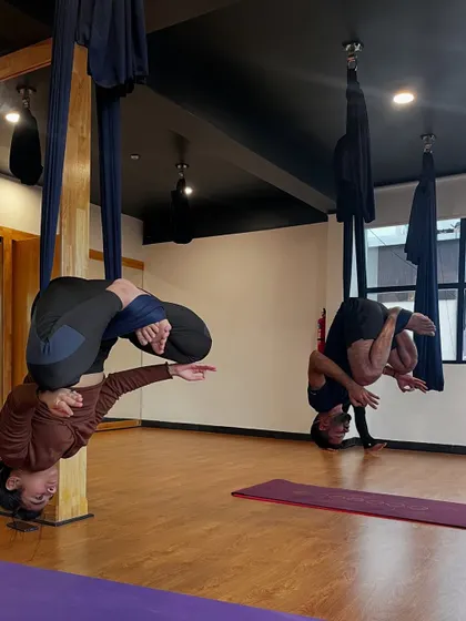Two students practice a challenging inverted pose, showcasing the strength and trust built in our classes.