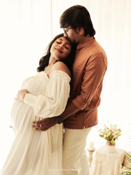 A tender embrace, with the father-to-be kissing his partner's forehead. This backlit shot creates a soft, dreamy, and romantic feel, perfect for a lifestyle session.