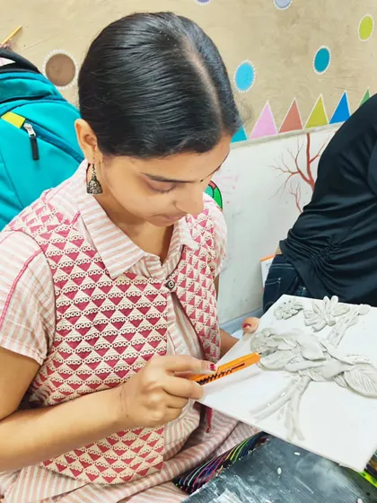 A student using tools to sculpt fine details into a clay relief panel. We teach the proper use of sculpting tools to achieve professional results.