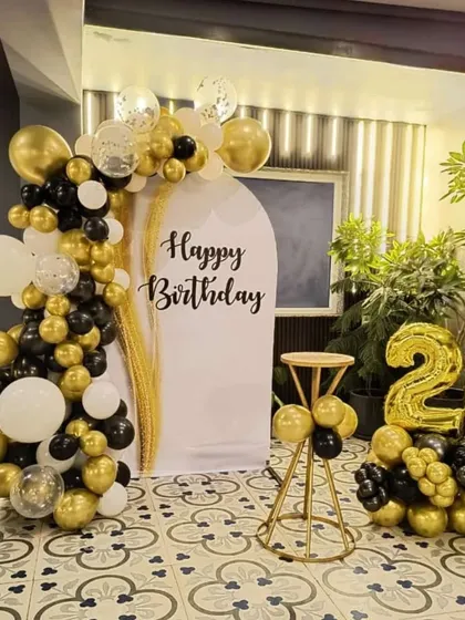 An elegant 26th birthday setup with a black, white, and gold theme. This decoration features a balloon arch on a custom backdrop, with number balloons on the side.