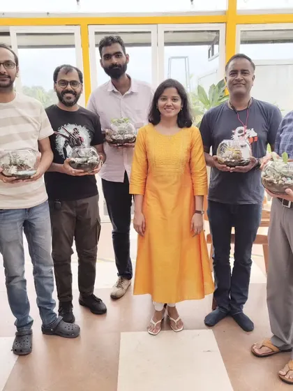 A group of friends proudly holding up the terrariums they made. This is a great activity for a small group looking for a unique and fun way to spend an afternoon.
