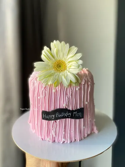 A pretty pink cake with a textured string-pull effect, topped with a fresh gerbera daisy. A lovely and simple design for a mom's birthday.