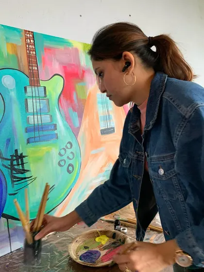 A candid shot of me working on a vibrant, abstract guitar painting. I love using bold colors and expressive brushstrokes to create a sense of energy and movement.