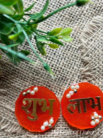 Simple and elegant red resin Shubh Labh discs with gold lettering and pearl accents. Perfect for a minimalist yet traditional festive look.