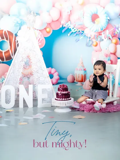 A round of applause for the birthday boy! This shot captures his happy expression as he sits on a little white chair, ready for his cake.