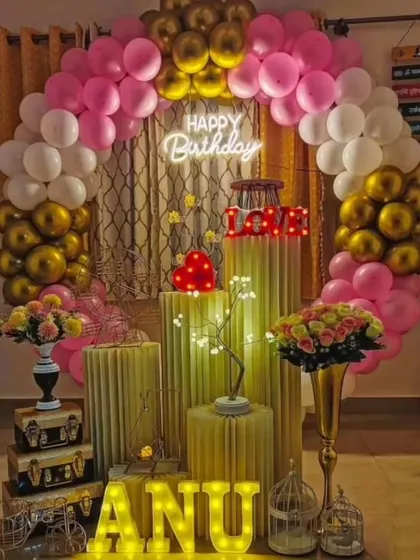 An elegant and romantic birthday decoration perfect for a surprise at home. The pink, white, and gold balloon arch, combined with light-up letters and props, creates a warm and celebratory feel.