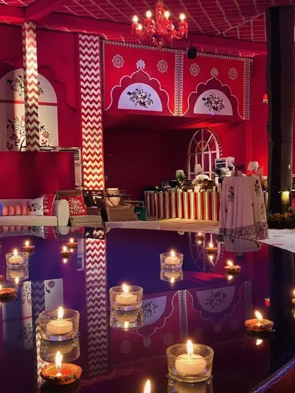 A beautiful detail from the 'Laal Ishq' event, where floating candles create reflections of love on a water surface. The background shows the rich red and white decor of the venue.
