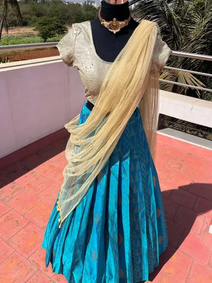 The simple elegance of this blue and gold half saree makes it a versatile choice.
