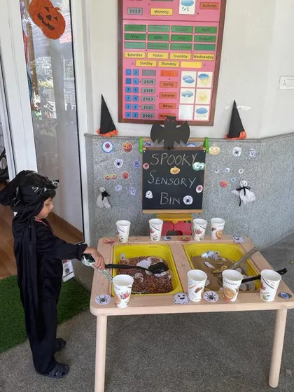 Dressed up and ready for some spooky fun. This little one is exploring the textures and objects in our Halloween-themed sensory bin, a perfect activity for tactile learning and imaginative play.