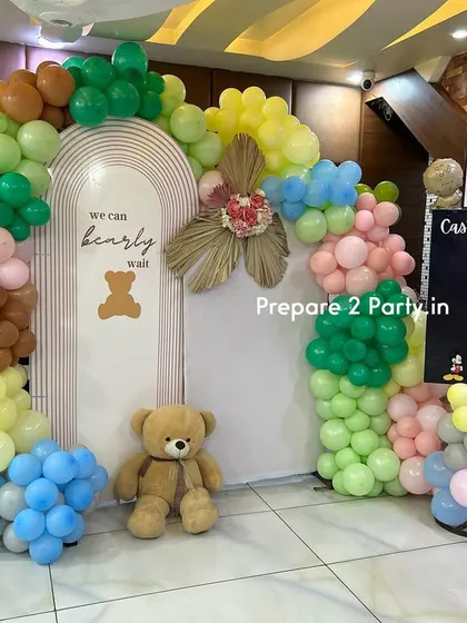 A fun and colorful "We Can Bearly Wait" baby shower theme. This setup includes a multi-colored balloon arch, a cute teddy bear prop, and an interactive "Cast Your Vote" board for a gender reveal game.