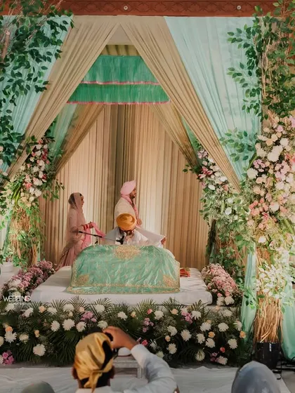 A beautiful Anand Karaj setup. We used soft drapes in mint green and gold, with floral pillars to create a serene and respectful space for the Sikh wedding ceremony.