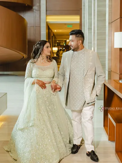 A stylish portrait of the couple walking hand-in-hand down a hotel corridor.