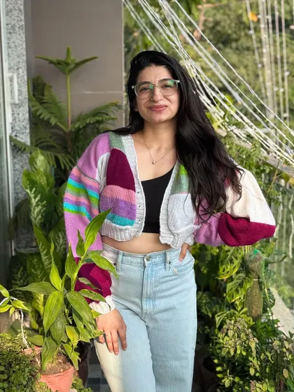 This patchwork cardigan features a unique color combination of purple, pink, and white. It's a one-of-a-kind piece that showcases our love for creative color palettes and cozy, chunky designs.