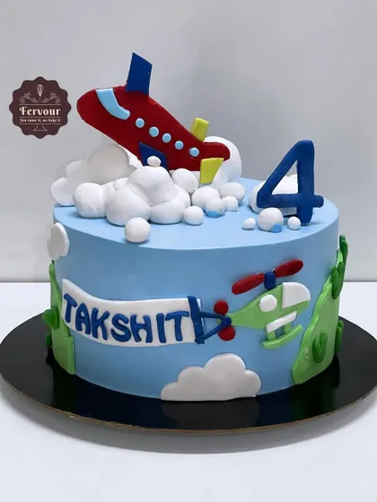 An airplane-themed cake for a 4th birthday celebration. The design features a fondant plane flying through fluffy whipped cream clouds, with a helicopter and banner adding to the sky-high fun.