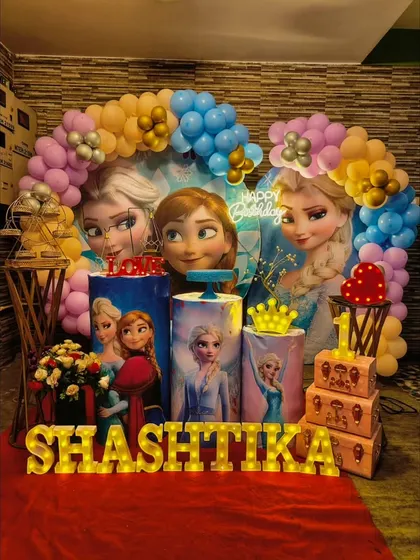 Let it go with our Frozen themed party decor. This setup for Shashtika's first birthday features Elsa, Anna, and Olaf with a blue and purple balloon arch that looks like a winter wonderland.