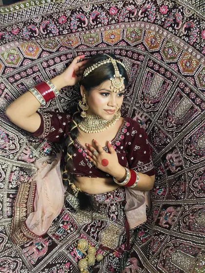 Another angle of this gorgeous bridal look, showing how the hair is styled with a traditional maang tikka and braid. The pose highlights the intricate details of the lehenga and jewellery.