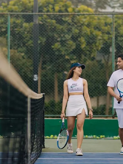 A walk and talk on the tennis court. This candid shot captures the natural interaction and friendship between the couple during their themed pre-wedding shoot.