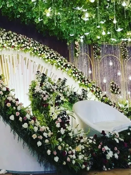 An angled view of the white-themed stage, highlighting the layers of the backdrop and the hanging light bulb details. This setup is perfect for an elegant garden or resort wedding.