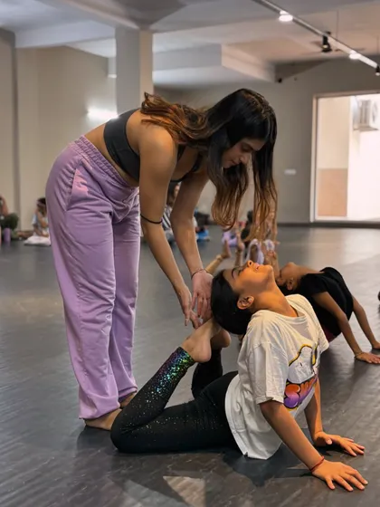 We believe in nurturing every dancer's potential. Here, one of our instructors provides gentle, hands-on guidance to help a young student safely deepen her backbend and improve her flexibility.