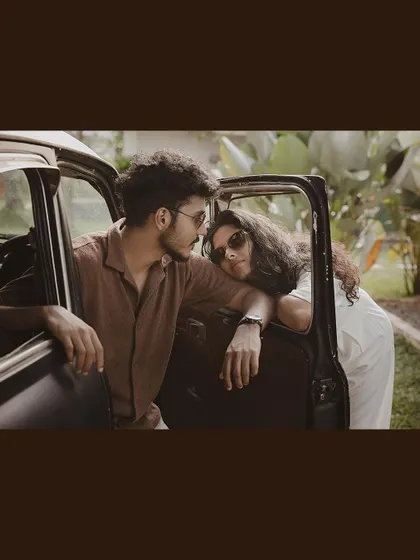 An intimate and stylish shot of a couple leaning out of a vintage car window.